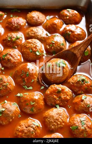 Nahaufnahme von Fleischbällchen mit Tomatensauce in der Backform. Selektiver Fokus Stockfoto