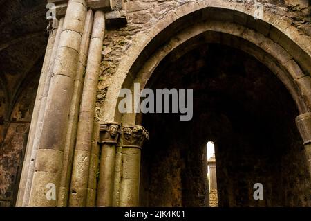 Geschnitzte Kapitelle und gotischer Bogen in den Ruinen der Corcomroe Abbey in Burren, Irland. Stockfoto