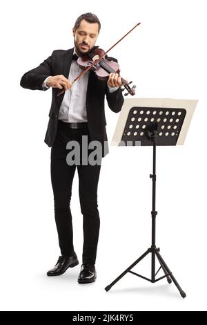 In voller Länge Porträt eines eleganten Mannes, der eine Geige spielt, mit einem Notenständer, der auf weißem Hintergrund isoliert ist Stockfoto