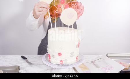 Einfügen von großen Lutscher mit Schneeflocken in den hohen Weiße, runde Kuchen als Dekoration. Stockfoto