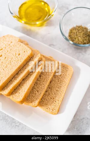 Gemessene Zutaten in Glasschüsseln zur Herstellung von Croutons. Stockfoto