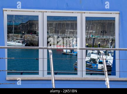 Reflejos en las ventanas de algunos barcos en el puerto de Lastres, Asturien, España Stockfoto