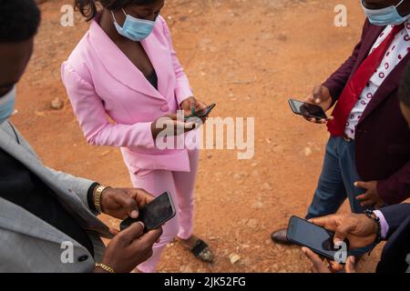 Während der Pandemie von Covid 19 nutzen vier Kollegen ihre Mobiltelefone während einer Arbeitspause. Stockfoto