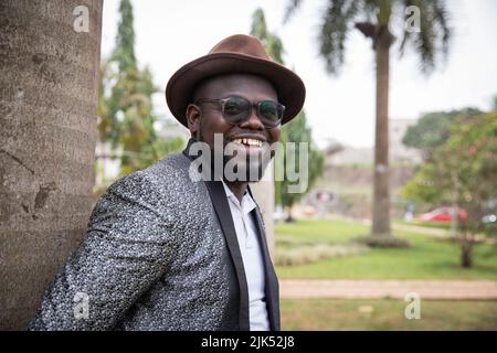 Ein stilvoller afrikanischer Geschäftsmann schaut im Park lächelnd herum. Outdoor-Konzept. Stockfoto