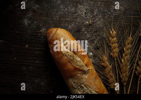 Baguette-Laib mit frischem Brot und Samen im rustikalen Stil. Hausgemachtes gesundes Brot backen Stockfoto
