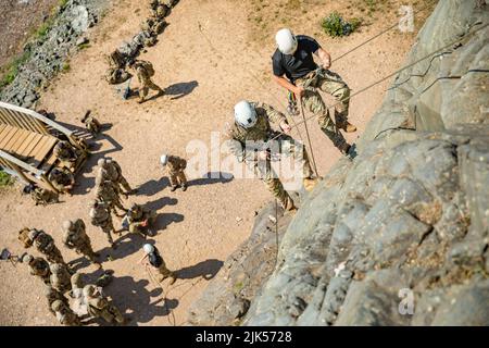 8. Juli 2022 - Delta Junection, Alaska, USA - Bergsteigerlehrer vom Northern Warfare Training Center Staff Sgts. Jordan Weeg, rechts, und Garrett Phillips, links, seilen eine Felswand herunter, während 11. Soldaten der Airborne Division während des Advanced Military Mountaineering Course am 8. Juli auf dem Trainingsgelände von Black Rapids von unten beobachten. Der Zweck des 14-tägigen Kurses ist es, Soldaten darin zu Schulen, wie sie durch bergiges Gelände manövrieren und dann zu ihren Einheiten zurückkehren und die Techniken und Verfahren zur Verfügung stellen, um über das bergige Gelände von Alaska zu gelangen. (Bild: © U.S. Army/ZUMA Press Wir Stockfoto