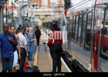 Zugunterbrechung nach einem Streik. Ein Bahnangestellter und Passagiere auf dem Bahnsteig einer Londoner U-Bahn-Station mit Waggons im Hintergrund Stockfoto