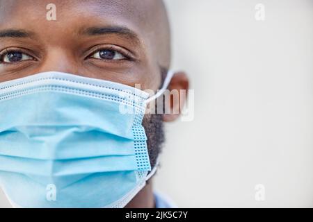 Tun Sie das Richtige und tragen Sie Ihre Maske. Nahaufnahme eines jungen Arztes, der bei der Arbeit eine Maske trägt. Stockfoto