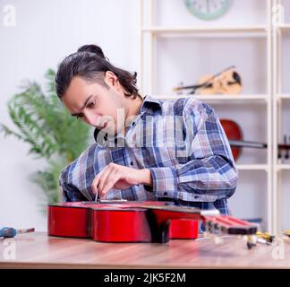 Die junge schöne Handwerker Reparatur Gitarre Stockfoto