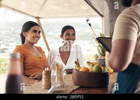 Es sollte in kürzester Zeit fertig sein. Zwei Freunde bestellen Lebensmittel von einem Food Truck. Stockfoto
