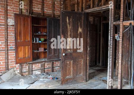 Das innere Skelett eines verlassenen Bauernhauses mit staubigen Geschirr im offenen Schrank. Stockfoto