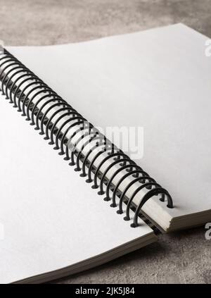 Geöffnetes Buch mit Spiralbindung auf der Tischplatte, leere und keine weißen Seiten, selektiver Fokus Stockfoto