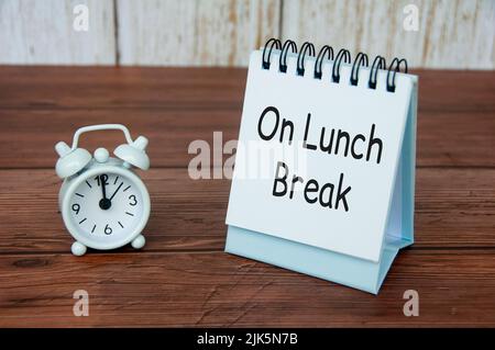 In der Mittagspause Text auf weißem Tischkalender mit Wecker, der auf 12pm zeigt. Bürokonzept Stockfoto