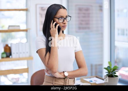 Sind Sie ernst? Eine attraktive junge Geschäftsfrau, die nachdenklich aussieht, während sie in ihrem Büro einen Telefonanruf abgibt. Stockfoto