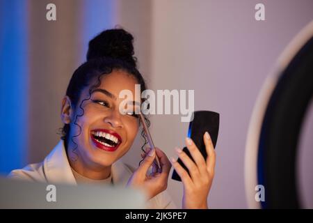 Du bist nie ganz angezogen ohne ein bisschen Make-up. Eine junge Frau, die Make-up zu Hause. Stockfoto