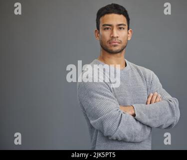 Ein hübscher junger Mann, der vor einem grauen Hintergrund steht. Stockfoto