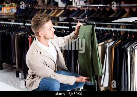 Mann, der sich für eine neue Hose entscheidet Stockfoto