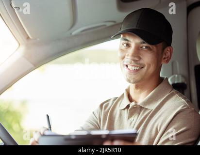 Überprüfen Sie immer Ihre Informationen. Ein Lieferer überprüft die Papiere für seine Lieferung in seinem Auto. Stockfoto