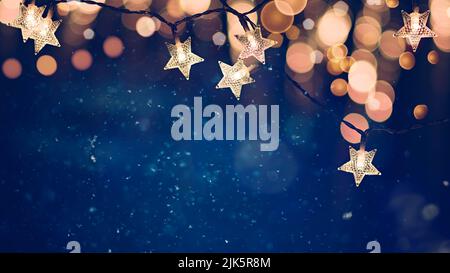 Sternförmige Weihnachtsschnur-Lichter auf blauem Nachthintergrund mit goldenen Bokeh-Lichtern Stockfoto