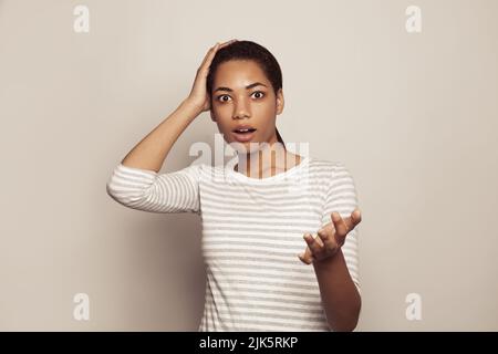 Nette Frau hält die Finger auf dem Kopf und sieht schockiert, Überraschungskonzept Stockfoto