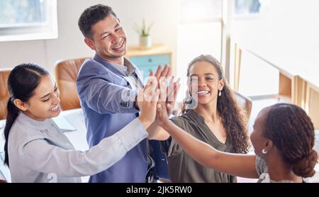 High Five für einen Job Gut gemacht. eine Gruppe von Kollegen, die ihre Hände in einem Büro bei der Arbeit zusammenlegen. Stockfoto