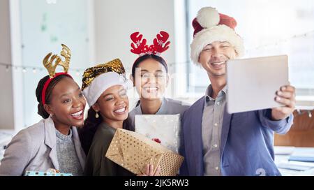Feiern Sie Weihnachten mit guten Menschen. Eine Gruppe von Kollegen, die ein Selfie machen, während Sie Weihnachten bei der Arbeit feiern. Stockfoto