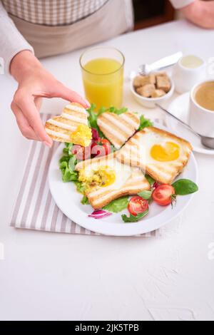 Herzförmiges gebratene Eier auf Toastbrot und eine Tasse frischen, heißen Espresso Stockfoto