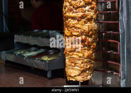 Nahaufnahme der gestapelten Fleischröstung, die für die Zubereitung von traditionellen griechischen Gyros oder türkischen Durum-Dönern verwendet werden kann. Kopierbereich mit verschwommenem Hintergrund Stockfoto