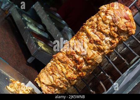 Nahaufnahme der gestapelten Fleischröstung, die für die Zubereitung von traditionellen griechischen Gyros oder türkischen Durum-Dönern verwendet werden kann. Kopierbereich mit verschwommenem Hintergrund Stockfoto