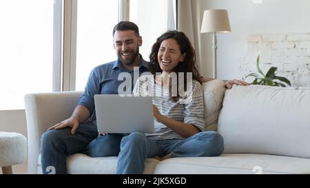 Glücklich überglücklich Millennial Paar mit Laptop zu Hause zusammen Stockfoto