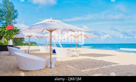 Luxuriöse Strandliegen und Sonnenschirme am Strand, mit Stühlen und weißen Sonnenschirmen am Strand in Phuket Thailand. Stockfoto