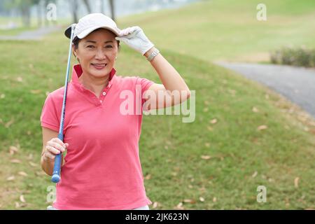 Portrait glückliche asiatische Golfspielerin mit einem Club Stockfoto