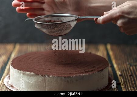 Traditionelles italienisches Dessert, Tiramisu-Kuchen wird oben durch das Kakaosieb-Pulver verziert. Hausgemachtes glutenfreies Tiramisu. Das Konzept der gesunden n Stockfoto