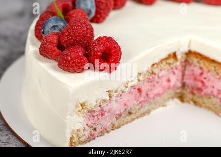 Köstlicher Himbeerkuchen mit Rahm und dekoriert mit frischen Himbeer-Beeren und Minzblättern Stockfoto