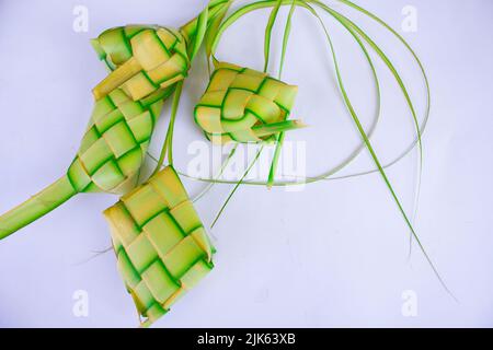 Ketupat in Steingutplatte isoliert auf weißem Hintergrund. Ketupat (Reisknödel) ist ein Essen, das serviert wird, wenn idhul fitri (eid mubarak) in Indonesien, Fr. Stockfoto