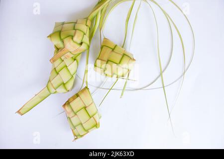 Ketupat in Steingutplatte isoliert auf weißem Hintergrund. Ketupat (Reisknödel) ist ein Essen, das serviert wird, wenn idhul fitri (eid mubarak) in Indonesien, Fr. Stockfoto