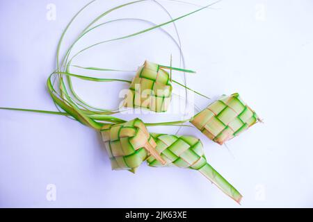 Ketupat in Steingutplatte isoliert auf weißem Hintergrund. Ketupat (Reisknödel) ist ein Essen, das serviert wird, wenn idhul fitri (eid mubarak) in Indonesien, Fr. Stockfoto