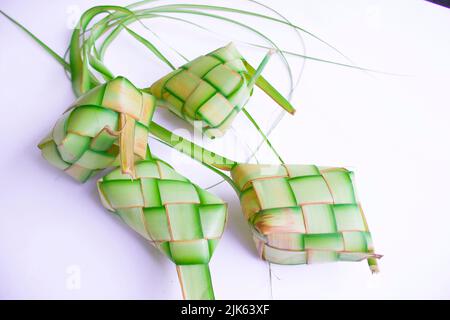 Ketupat in Steingutplatte isoliert auf weißem Hintergrund. Ketupat (Reisknödel) ist ein Essen, das serviert wird, wenn idhul fitri (eid mubarak) in Indonesien, Fr. Stockfoto