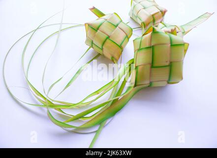 Ketupat in Steingutplatte isoliert auf weißem Hintergrund. Ketupat (Reisknödel) ist ein Essen, das serviert wird, wenn idhul fitri (eid mubarak) in Indonesien, Fr. Stockfoto