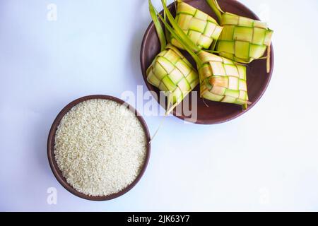 Ketupat in Steingutplatte isoliert auf weißem Hintergrund. Ketupat (Reisknödel) ist ein Essen, das serviert wird, wenn idhul fitri (eid mubarak) in Indonesien, Fr. Stockfoto