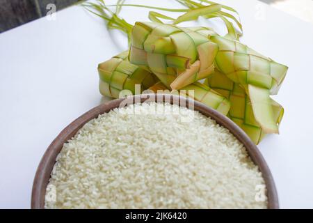 Ketupat in Steingutplatte isoliert auf weißem Hintergrund. Ketupat (Reisknödel) ist ein Essen, das serviert wird, wenn idhul fitri (eid mubarak) in Indonesien, Fr. Stockfoto