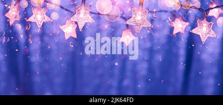 String-Leuchten in Form von Sternen mit Bokeh-Lichtern auf einem glänzenden Hintergrund in den Farben von 2022 Stockfoto