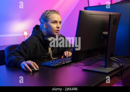 Fokussierte professionelle E-Sport-Gamer Mädchen in Hoody Online-Video spielen Spiel auf dem PC Stockfoto