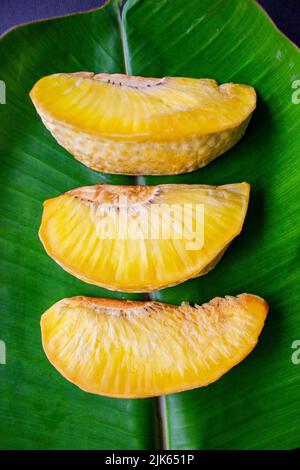 sukun Goreng oder gebratene Brotfrucht serviert auf Bananenblatt auf schwarzem Hintergrund Stockfoto