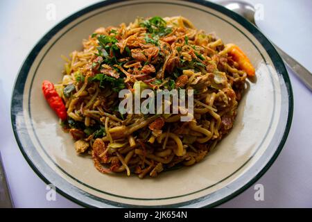 'Mie Goreng Jawa oder Bakmi jawa oder java Nudel mit Löffel und Gabel. Indonesische traditionelle Street Food Nudeln aus Zentral-java oder Yogyakarta, Indone Stockfoto