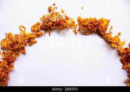 bawang goreng oder Haufen gebratener indonesischer Fritten oder Schalotten mit kreisförmiger Isolierung auf weißem Hintergrund. Stockfoto