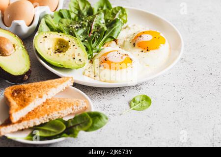 Gesundes Frühstück mit Vollkornbrot Toast, Eier mit grünem Salat, Avocado. Traditionelles Frühstück Stockfoto