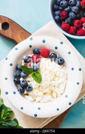 Hausgemachter Hüttenkäse mit Beeren und Minze. Quark in einer Schüssel. Milchprodukte. Stockfoto