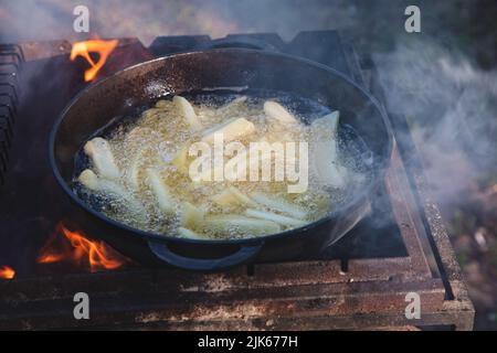 Der Prozess des Kochens von pommes auf einem Feuer in einem Kessel. Zeit für ein Picknick. Stockfoto