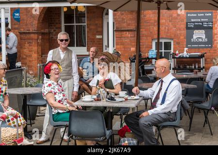 Menschen, die in Kleidungsstücken der 40er Jahre gekleidet waren, genießen eine Pause am Lawn Lincoln Wochenende der 40er Jahre, Lincoln Cathedral Quarter, 23.. Juli 2022 Stockfoto